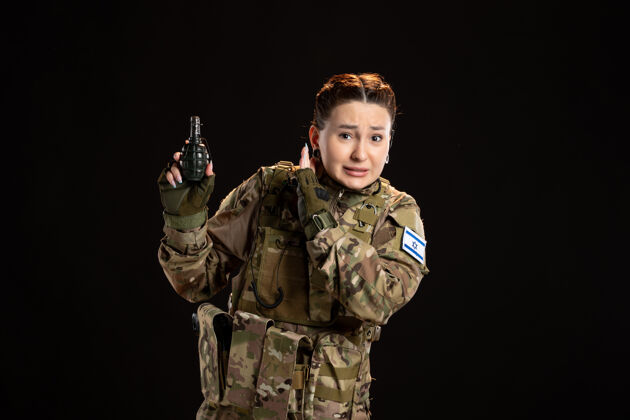 肖像身穿迷彩服的女兵手里拿着手榴弹站在黑墙上女人封面人