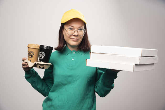 年轻人女送货员拿着一个白色的纸板咖啡杯高品质的照片眼镜帽子女士