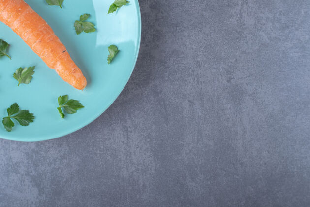 新鲜一根胡萝卜放在盘子里 上面是绿色的 放在大理石表面上胡萝卜农业营养