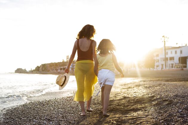 全镜头全场拍摄的海滩上的女人和女孩假期家庭生活方式