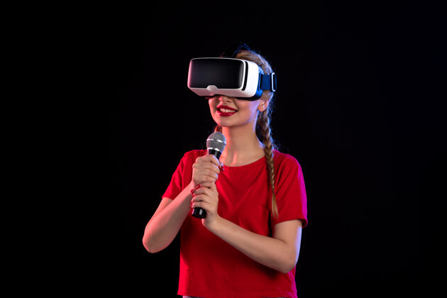 娱乐在黑暗的音乐视觉超声波游戏中 年轻女士在玩虚拟现实和唱歌的肖像虚拟现实音乐家表演