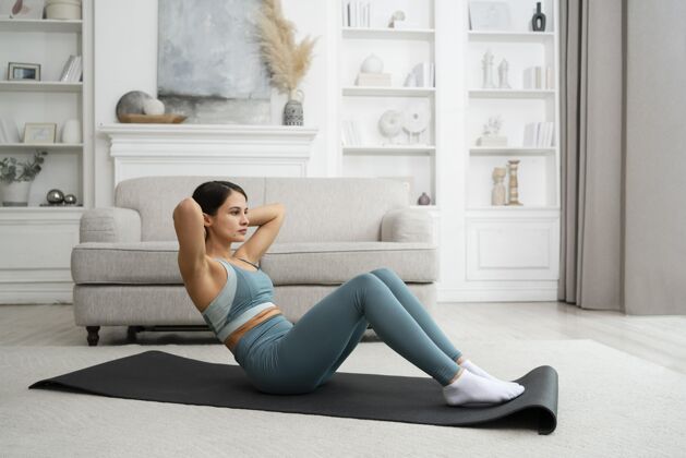训练在家里用健身垫锻炼的年轻女子身体女人在家锻炼
