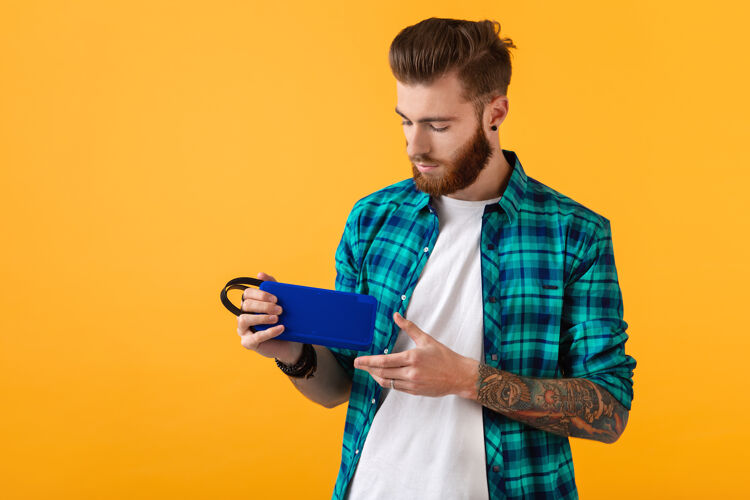 欢乐时尚微笑的年轻人手持无线扬声器听音乐扬声器科技胡须