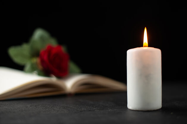 开放打开的书和蜡烛上的黑玫瑰的正面视图火死亡地板