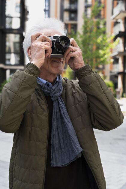 老年人时尚的老男人在城市里用相机拍照城市成熟老年人