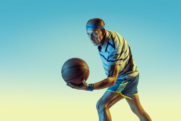 姿势穿运动服的高级男士在渐变背景下打篮球 霓虹灯身材魁梧的白人男模保持活跃运动 活动 运动 健康 自信的概念球员比赛老年人