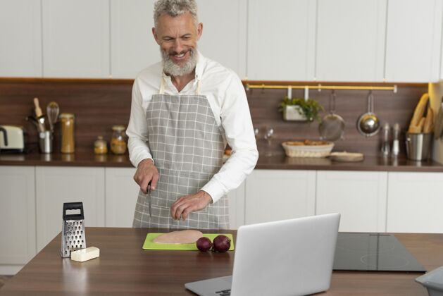 厨房家里的老人在厨房用笔记本电脑上烹饪课成人设备水平
