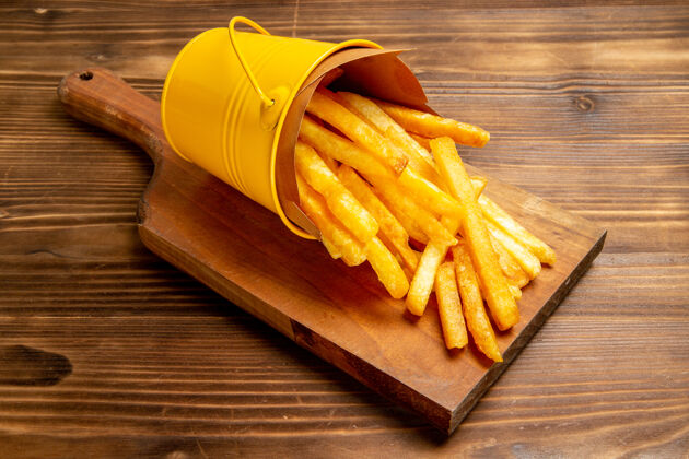 薯条正面图：棕色办公桌上小篮子里的薯条土豆快餐汉堡餐食物里面一餐