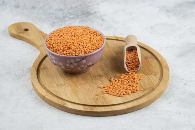 生的一碗生的红扁豆和勺子放在砧板上有机扁豆木头