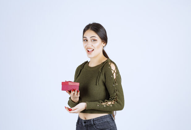 人微笑的女人拿着礼品盒 看着白色背景上的相机积极举行年轻