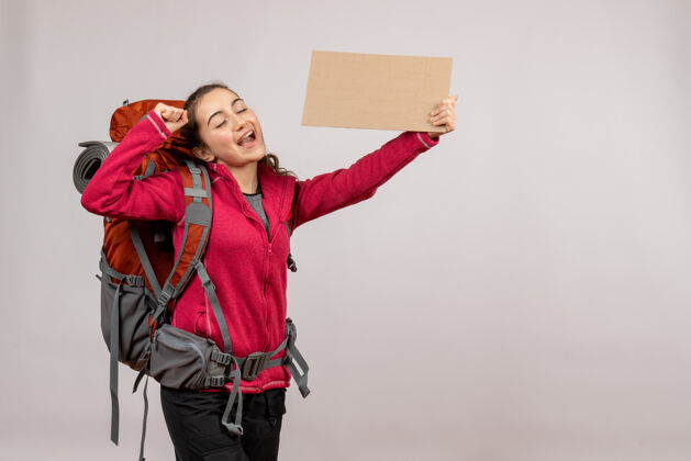 漂亮正面图：年轻的旅行者背着大背包举着纸板度假标志搭便车