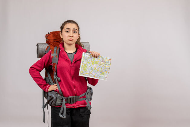 旅游正面图：年轻的旅行者背着大背包 手放在腰上拿着地图肖像旅行者背包