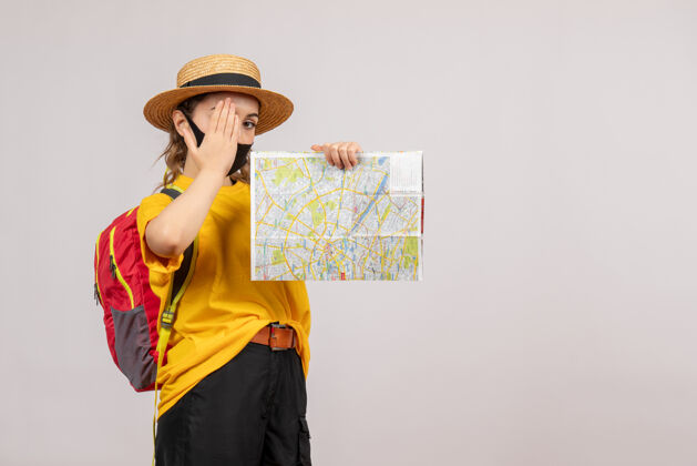 女人正面图：年轻的旅行者背着背包 举着地图 手放在眼睛上地图肖像面具