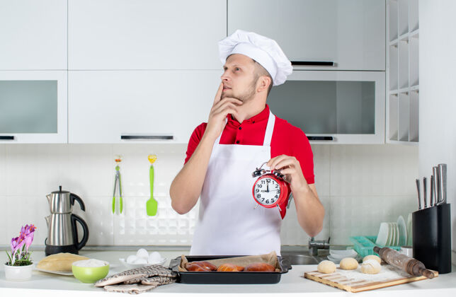 厨房白色厨房里年轻的梦幻男厨师手持时钟的俯视图人男性切肉刀