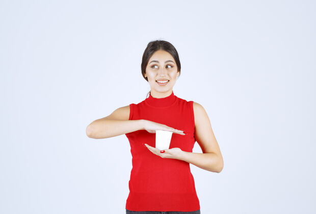 女人一个穿红衬衫的女孩双手捧着一个白色的咖啡杯女性职员服装