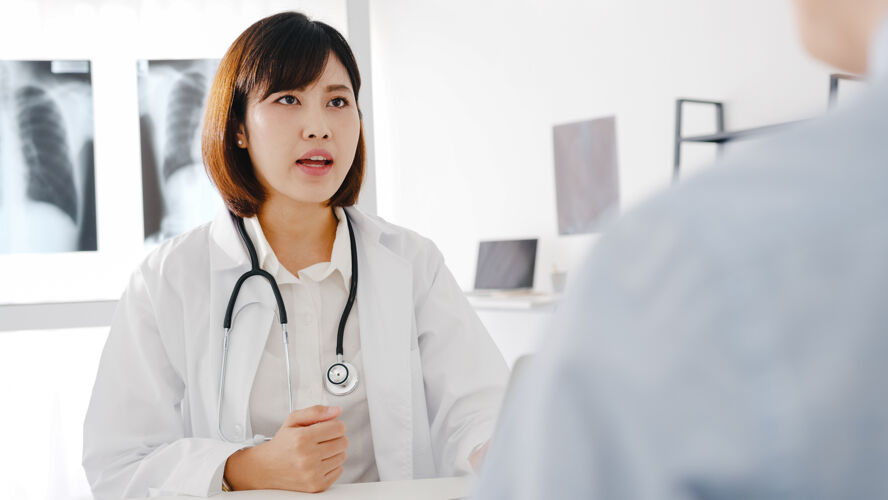 疾病年轻的亚洲女医生穿着白色的医疗制服 用笔记本电脑发表精彩的新闻谈话 讨论结果预约信心护理