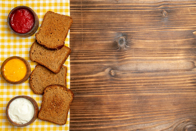 早餐顶视图黑面包面包与调味料棕色木制桌子面包辣味调味料捕获景观胸部