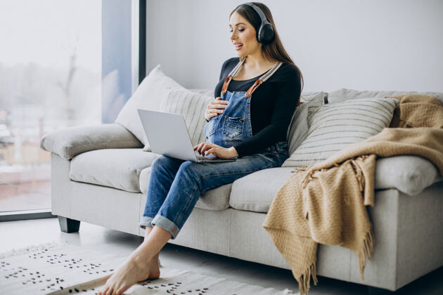 腹部孕妇戴着耳机听音乐上网产前怀孕音乐