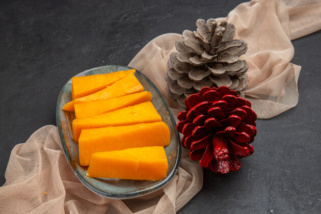 食用水果上图：黑色背景下 毛巾上的美味奶酪片和针叶树球果蔬菜农产品玫瑰