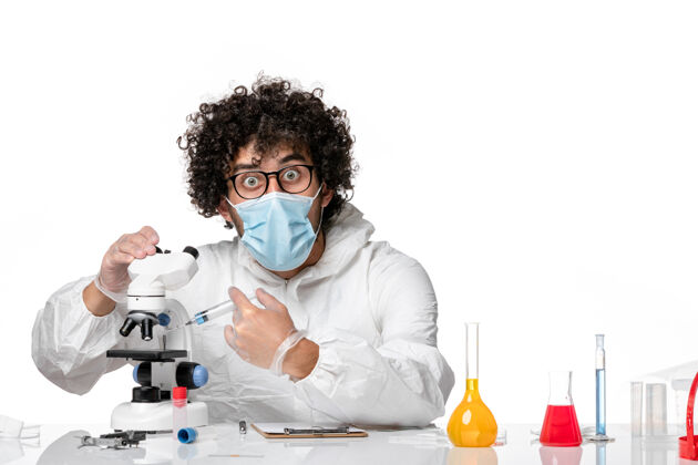 工作男医生穿着防护服 戴着口罩 用显微镜在浅白上工作流行病实验室人
