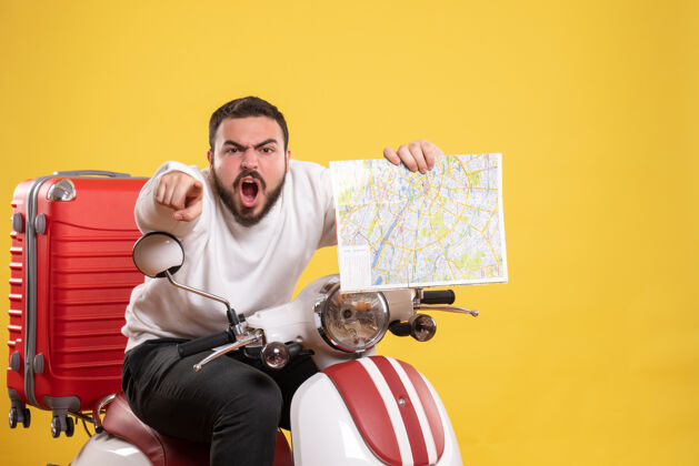 运动一个愤怒的家伙坐在摩托车上 手提箱放在上面 手里拿着黄色的地图 指着前方主动手提箱成人