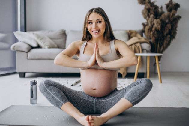 瑜伽练习孕妇在家里的垫子上练习瑜伽为人父母怀孕瑜伽