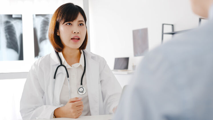 疾病年轻的亚洲女医生穿着白色的医疗制服 用笔记本电脑发表精彩的新闻谈话 讨论结果预约信心护理