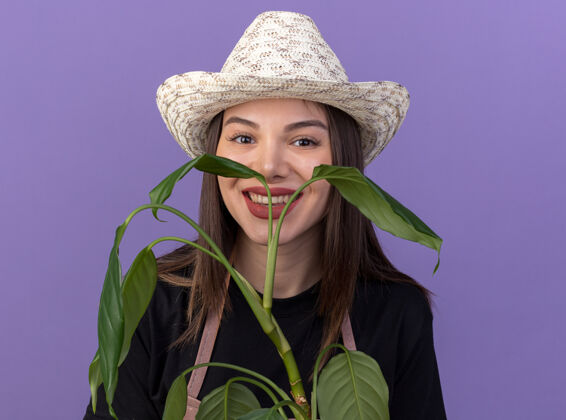 园艺笑容可掬的高加索女园丁戴着园艺帽捧着植物枝帽子微笑女