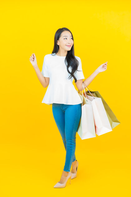 包一幅美丽的亚洲年轻女子微笑的画像 黄色的购物袋持有买家女性