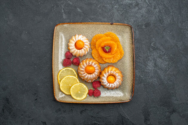 水果俯瞰图美味的小蛋糕柠檬片和橘子上的深色背景水果饼干甜茶饼干饼干约束托盘