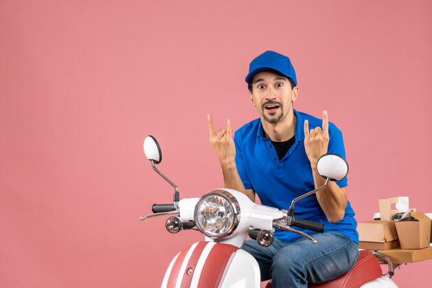 背景前视图疯狂的情感信使家伙戴着帽子坐在粉彩桃背景踏板车人物粉彩滑板车