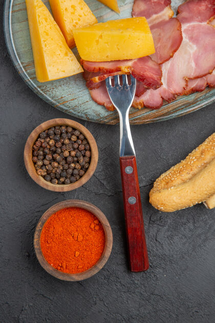 深色蓝色盘子上美味的香肠和奶酪片的垂直视图 黑色背景上的辣椒午餐晚餐烹饪