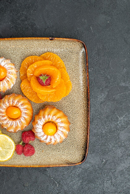 饼干俯瞰图美味的小蛋糕柠檬片和橘子在一个黑暗的背景水果饼干甜茶饼干派蛋糕橘子面包