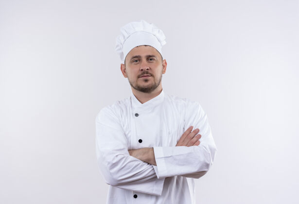 烹饪自信的年轻帅哥厨师身着厨师制服 以封闭的姿势站在白色的墙上厨师姿势封闭