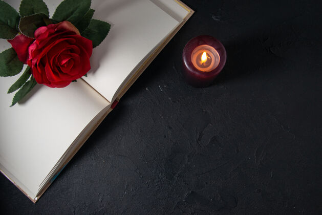 红打开的书的顶视图 黑暗的墙上有蜡烛和红花花葬礼视图