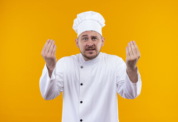 年轻年轻帅气的厨师穿着厨师制服 举起的手孤立在橙色的墙上厨艺帅气手