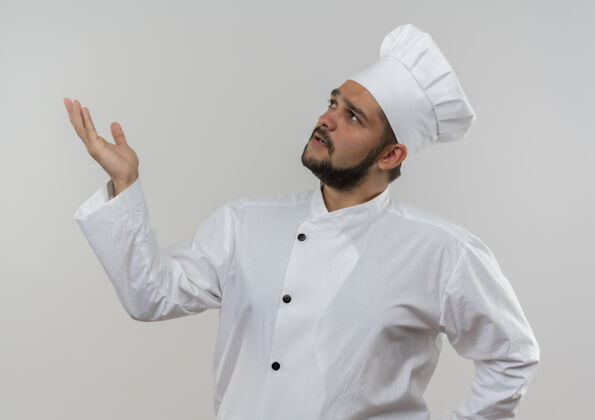 显示穿着厨师制服的年轻男厨师抬起头来 在白色的墙上孤零零地伸出空手 给人留下了深刻的印象男性烹饪印象