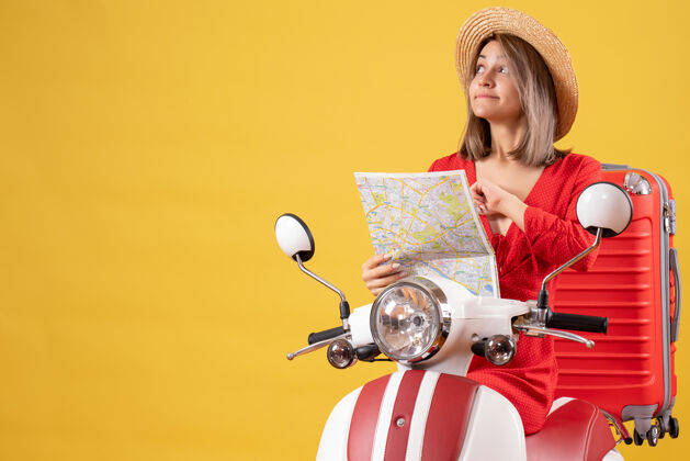 女商人穿着红色衣服的漂亮女孩骑着轻便摩托车 带着红色手提箱拿着地图衣服漂亮女孩手提箱