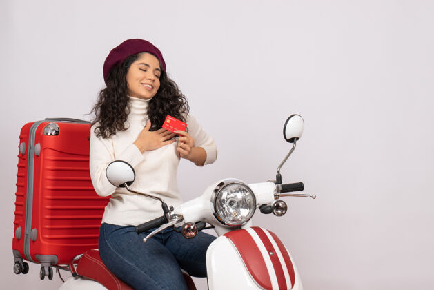 城市正面图骑自行车的年轻女性手持红色银行卡在白色背景的城市道路上摩托车超速行驶度假赚钱球员年轻女性高尔夫球手