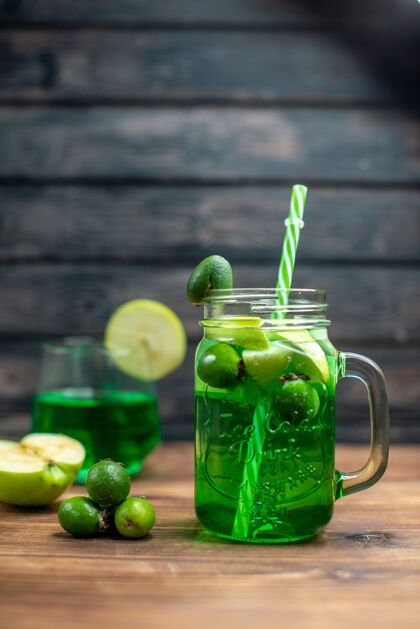 前面正面图绿色的菲乔果汁罐里面有绿色的苹果 放在木制的桌上吧水果色的鸡尾酒饮料照片水果酒吧里面