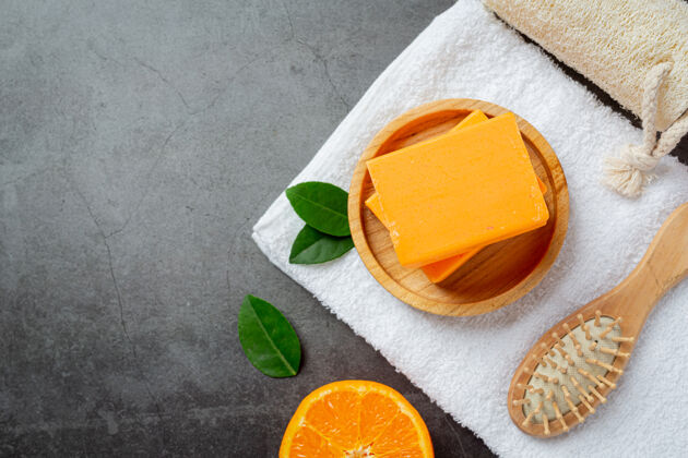 浴室橙色肥皂与新鲜的橙色在黑暗的背景草药产品身体护理