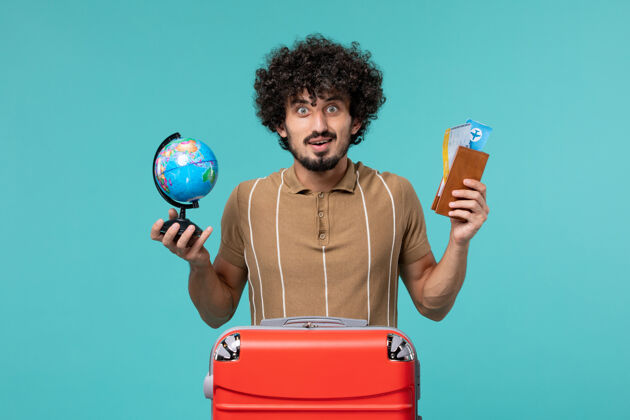 男人前视图中的度假男子拿着地球仪和蓝色的机票地球仪蓝色票