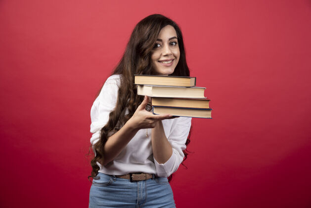 人年轻女子拿着红色背景的书高质量的照片教科书女孩肖像