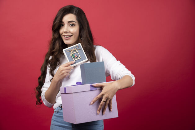女性在红色背景上展示礼物的年轻女子高质量照片礼物盒子女人