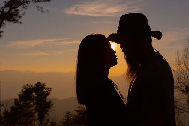 人在山上欣赏日落的年轻夫妇相聚男性遥远