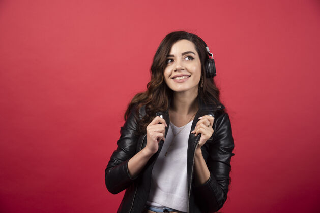 独自戴着耳机听音乐 在红色背景上摆姿势的年轻女子高质量照片耳机女性女人