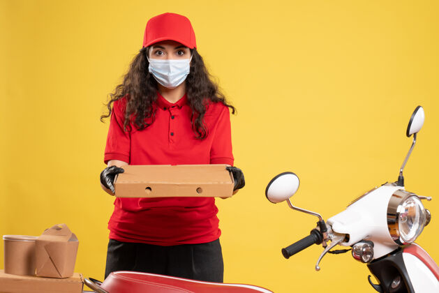 披萨前视图穿着红色制服的女快递员 黄色背景上有披萨盒 工作人员递送病毒-大流行服务病毒工作人工人肖像