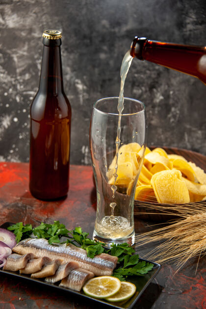 小吃前视图新鲜鱼片配绿色蔬菜和啤酒深色照片小吃肉食海鲜色葡萄酒瓶子杯子