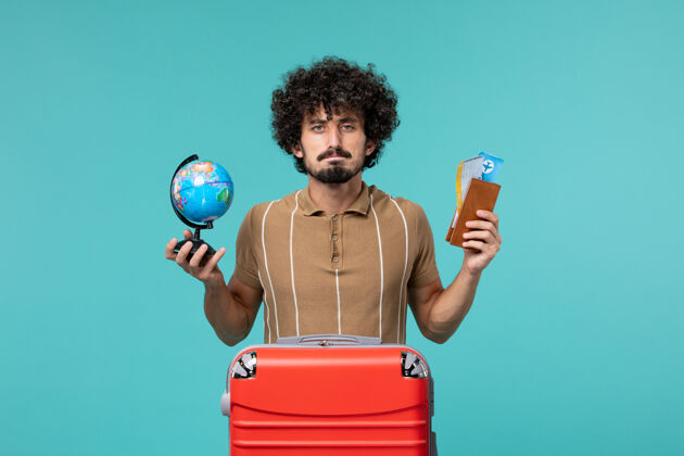 航行前视图中的度假男子拿着地球仪和蓝色的机票旅行地球仪假期