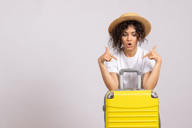 年轻女性正面图年轻女性带着黄色的包准备在白色的背景上旅行阳光色彩远航度假飞机休息游客微笑人旅行